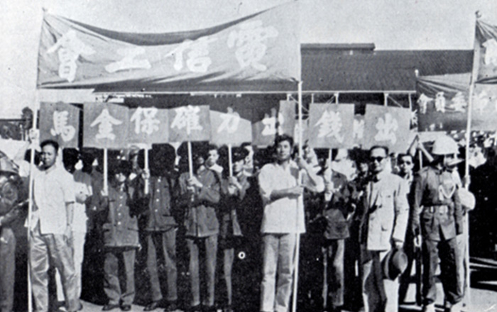 今天是小時候最熱鬧的國家慶典-雙十節。 台灣50、60年代的10月10日，政府會事先訂定年度國家宣傳方向，全台會動員100多個公民營工商事業團體，北上到總統府前遊行，除了部份規模較大的單位會出動卡車造勢，主要都是人力手舉口號布旗。可別看走路很容易，事先可都要排演預練至少3個月，才能有列隊齊走的浩蕩陣容呢！ 圖為民國64年的「國慶日電信工會遊行」，那年毋忘在莒、保家衛民是國家公布的宣導重點，所以布旗除了「電信工會」，就是醒目的「出錢出力、確保金馬」。